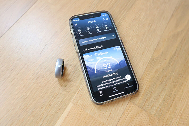 Oura Ring liegt neben der Handy-App auf dem Tisch